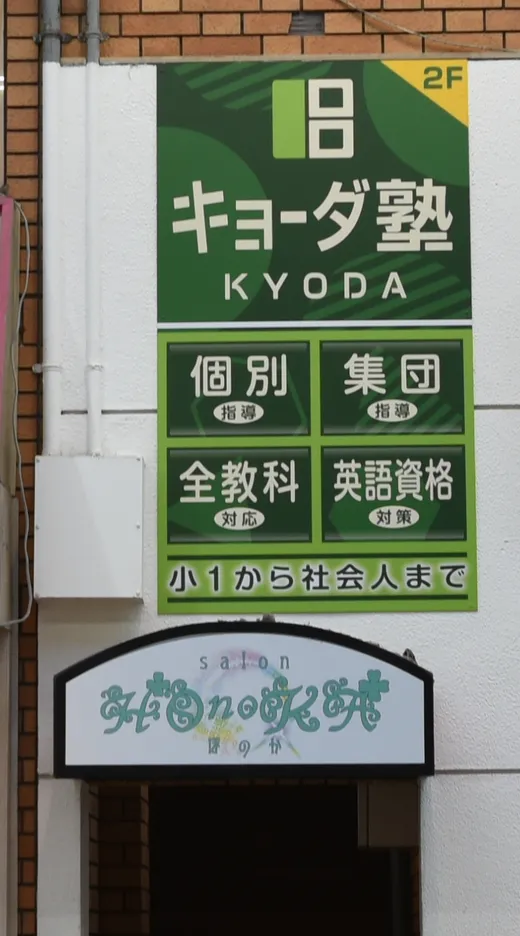 会場の入口。緑色の「キョーダ塾」の看板と、そのすぐ下にある2階へ上がる入口。